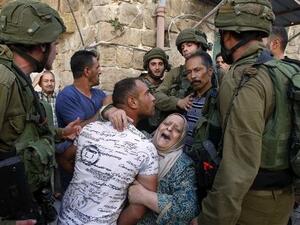 A Palestinian woman tries to prevent the arrest of a Palestinian man by Israeli soldiers in the southern occupied West Bank city of al-Khalil. (AFP/ File Photo)
