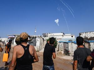 Men watch as tear gas canisters fired by the Turkish gendarmerie fall amidst clashes in a demonstration by displaced Syrians along the border with Turkey near the town of Atme in the northwestern Idlib province on August 30, 2019. (AFP/ File Photo)