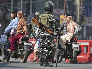 Indian paramilitary troopers stop Indian Kashmiri motorcyclists during a strict curfew in Lal Chowk (AFP)