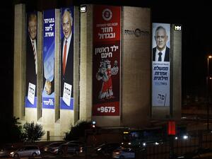Israeli election banners and advertising hanging from a building in Jerusalem, (L to R) for the Likud party showing US President Donald Trump shaking hands with Likud chairman and Prime Minister Benjamin Netanyahu with a caption in Hebrew reading "Netanyahu, in another league"; an advertisement for Hapoel Jerusalem Basketball Club; and for the "Blue and White" (Kahol Lavan) electoral alliance showing the face of retired general Benny Gantz and a caption in Hebrew reading "only with the Blue and White will c