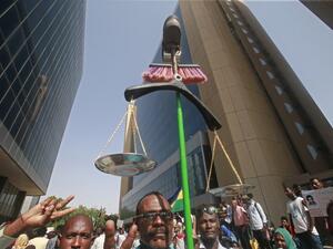 A Sudanese protester carries makeshift scales during a protest asking for the extradition of ousted former president Omar al-Bashir to the International Criminal Court in the capital Khartoum on September 19, 2019. (ASHRAF SHAZLY / AFP)