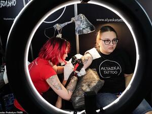 Another brave woman undergoes a long process to have her tattoo on her arm completed by one of the talented artists at the exhibition. (Sokolniki Exhibition and Convention Centre)