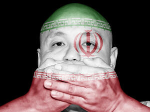 A man covering his mouth with his hand with imprint of Iran flag (Shutterstock)	