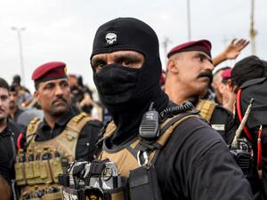 Iraqi security forces confront protesters during a demonstration against corruption and lack of basic services in the central Iraqi shrine city of Najaf (AFP)