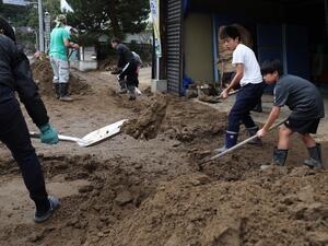 Residents clear mud from a street at the flooded area in Marumori, Miyagi prefecture on October 14, 2019, in the aftermath of Typhoon Hagibis. Tens of thousands of rescue workers were searching for survivors of powerful Typhoon Hagibis, two days after the storm slammed into Japan, killing at least 35 people. (Jiji Press / AFP)