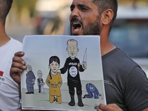 A man shouts slogans while holding up a sign showing a cartoon depicting current Turkish President Recep Tayyip Erdogan dressed in an Islamic State (IS) group uniform showing the group's logo and holding up a knife next to a woman dressed in an orange jumpsuit reading "Kurdistan"  (AFP)