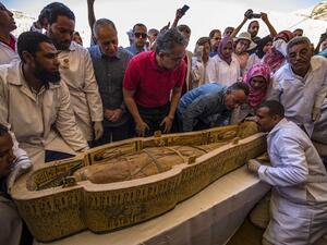 Egypt's Antiquities Minister Khaled el-Enany (4-R), and Mostafa Waziri (3-R), the Secretary General of the Supreme Council of Antiquities, surround a sarcophagus belonging to a man in front the Hatshepsut Temple at the Valley of the Kings in Luxor on October 19, 2019. Khaled DESOUKI / AFP