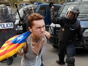 A Spanish national police officer uses his club to hit a protester during a demonstration called the Catalan pro-independence left youth group 'Arran' (AFP)