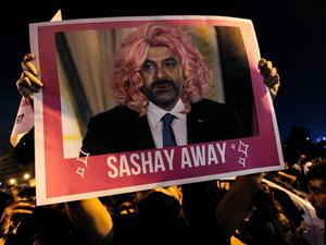 A Lebanese protester lifts a picture of Prime Minister Saad Hariri in a wig during a rally in downtown Beirut on the third day of demonstrations against tax increases and official corruption, on October 19, 2019. The writing "sashay away" refers to a catchphrase from a drag queen TV show meaning "leave". IBRAHIM AMRO / AFP