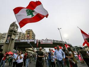 A man waves a Lebanese national flag during a demonstration on the highway that links the capital Beirut to the northern city of Tripoli, in the area of Jal el-Dib in the northeastern outskirts of the capital, on October 26, 2019 on the tenth day of protest against tax increases and official corruption. (JOSEPH EID / AFP)