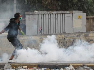 An Iraqi demonstrator runs through a cloud of tear gas during continuing anti-government protests in the centre of Baghdad on October 27, 2019. The Iraqi capital and south have been rocked by a second wave of demonstrations since October 24, with protesters persevering despite tear gas, curfews and violence that has left over 60 dead. (AFP/ File Photo)