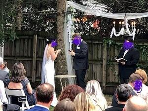 Newlyweds, believed to be from the US, are both typing away on their phones as they stand next to their officiant in a photograph (pictured) shared on social media, last week (Facebook)