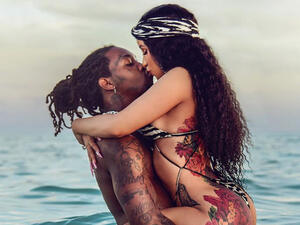 Cardi's long natural curls cascade over her shoulders in waves. 