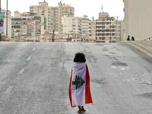 A Lebanese woman protester walks draped in a national flag along the Fuad Chehab avenue, near the Martyrs' Square, in the centre of the capital Beirut on October 29, 2019. (AFP/ File Photo)