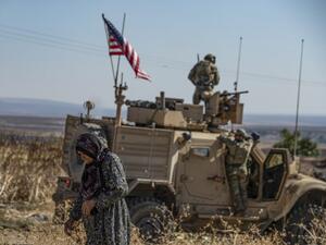 A Syrian elderly woman walks past a US armoured vehicle on patrol in the village of Ein Diwar in Syria's northeastern Hasakeh province on November 4, 2019.  Delil SOULEIMAN / AFP