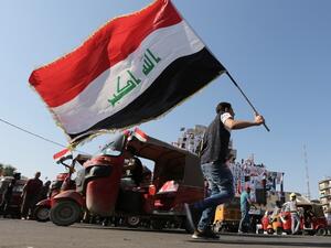 An Iraqi protester waves the natioanl flag in Tahrir square in the capital Baghdad on November 5, 2019, amid ongoing anti government demonstrations. Iraqi security forces fired live rounds yesterday at protesters in Baghdad, after four demonstrators were shot dead overnight outside the Iranian consulate in the holy city of Karbala. (SABAH ARAR / AFP)