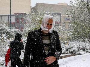 People walk under heavy snow in the Iranian capital Tehran on November 16, 2019. Heavy snowfall blanketed the streets of north Tehran causing traffic chaos and forcing the closure of schools, authorities in the Iranian capital said. Crews of municipal workers were battling to clear roads and pavements in parts of the capital, where snow began falling at the start of the morning rush hour and continued through the day. ATTA KENARE / AFP