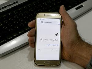 A man holds a smartphone connected to a Wifi network without internet access at an office in the Iranian capital Tehran on November 17, 2019. (AFP)