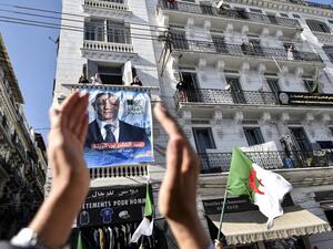 A supporters of Abdelkader Bengrina, former Algerian tourism minister and presidential candidate for the El-Bina (Construction) Islamist party, applauds outside his electoral campaign headquarters in the capital Algiers on November 17, 2019. (RYAD KRAMDI / AFP)