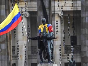 A man waves a national flag atop a statue of the Liberator Simon Bolivar during a protest against the government of Colombian President Ivan Duque in Bogota on November 27, 2019. Protest leaders in Colombia called a new general strike for Wednesday after a meeting with President Ivan Duque made no progress towards ending deadly anti-government demonstrations now in their sixth consecutive day. Juan BARRETO / AFP