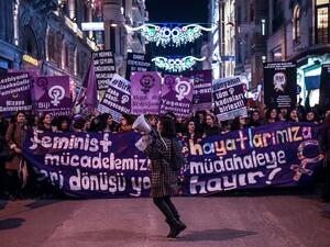 People hold signs as they march down Istiklal Avenue during a feminist night march to mark International Women's Day in Istanbul on March 8, 2017 (AFP Photo/OZAN KOSE)