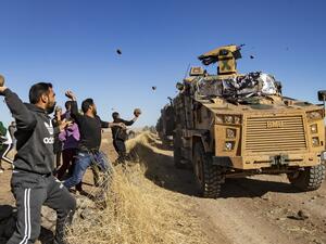 Kurdish demonstrators hurl rocks at a Turkish military vehicle on November 8, 2019, during a joint Turkish-Russian patrol near the town of Al-Muabbadah in the northeastern part of Hassakah on the Syrian border with Turkey. Delil SOULEIMAN / AFP
