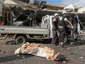 The body of a victim lies on the ground near members of the Syrian Civil Defence (White Helmets) following a regime air strike on December 2, 2019 in a market in the town of Maaret al-Numan in the jihadist-run Syrian province of Idlib. Regime air strikes killed 10 civilians and wounded at least 15 in Syria's last major opposition bastion, where deadly clashes between regime forces and armed groups have escalated in the past two days, the Britain-based Syrian Observatory for Human Rights added said. Abdulazi