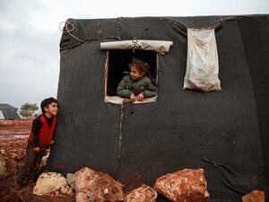 A boy and a girl looking out the window of a tent exchange glances, at a flooded camp for displaced Syrians near the village of Killi in the north of the northwestern Idlib province on December 5, 2019. Aaref WATAD / AFP