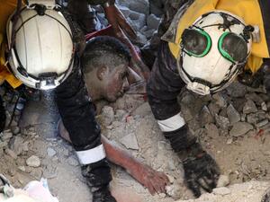 Members of the Syrian Civil Defence, also known as the White Helmets, rescue a survivor from the rubble of a collapsed building following a reported air strike in the village of Balyun in Syria's northwestern Idlib province on December 7, 2019. Syrian regime and Russian air strikes on December 7 killed over a dozen civilians, including children, in the country's last major opposition bastion of Idlib, the Syrian Observatory for Human Rights said. Abdulaziz KETAZ / AFP