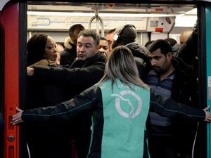 A Paris public transports operator RATP employee stands as commuters board on a RER B regional train at Chatelet-les Halles station in Paris on December 9, 2019 during a strike of RATP employees over French government's plan to overhaul the country's retirement system, as part of a national strike. (Aurore MESENGE / AFP)