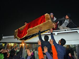 Mourners unload from the top of a bus a coffin draped in the Iraqi national flag in the central holy shrine city of Najaf on December 13, 2019, during the funeral of a teenager who was lynched and killed the previous day in Baghdad, as he was accused of attacking a protest encampment. (AFP/ File Photo)