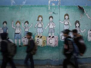 Palestinian children walk past a mural on their way to their United Nations-run school in Al-Shati refugee camp in Gaza City, on December 14, 2019. MOHAMMED ABED / AFP