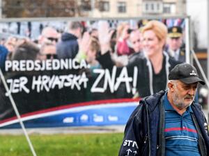 A man walks past a placard of the current Croatian President and candidate Kolinda Grabar-Kitarovic for the presidential election, from outside a window, in downtown Zagreb, December 21, 2019. Croatia voters will go to the polls on December 22, 2019 for the Croatian presidential election. Denis LOVROVIC / AFP