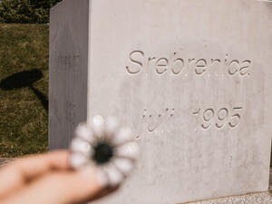 Srebrenica–Potočari Memorial and Cemetery for the Victims of the 1995 Genocide. Bosnian men were executed by the Bosnian Serb Army. Woman hand holding Srebrenica flower (Shutterstock)	
