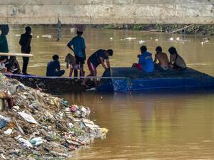 Young men wait under a concrete bridge looking to salvage valuable items carried by the currents in Jakarta on January 3, 2020, after flooding triggered by heavy rain which started on New Year's Eve hit the area. (AFP/ File Photo)