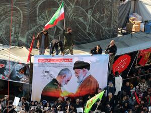 Iranian mourners carry a picture of Iran's Supreme Leader Ayatollah Ali Khamenei (R) granting the Order of Zolfaghar, the highest military honour of Iran, to General Qasem Soleimani, during the latter's funeral procession in the capital Tehran on January 6, (AFP/ File Photo)