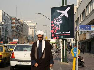 An Iranian cleric walks past a poster honouring the victims of a Ukrainian passenger jet accidentally shot down in the capital last week, in front of the Amirkabir University in the capital Tehran, on January 13, 2020.  (AFP/ File Photo)