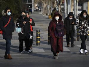 Pedestrians wearing masks cross a street in Beijing on January 21, 2020. The number of people in China infected by a new SARS-like virus jumped to 291 on January 21, according to authorities.  WANG Zhao / AFP