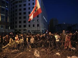 Lebanese anti-government demonstrators rally by barbed wire set by security forces to block a road leading to the government headquarters at the Grand Serail, in downtown Beirut, on January 25, 2020. ANWAR AMRO / AFP