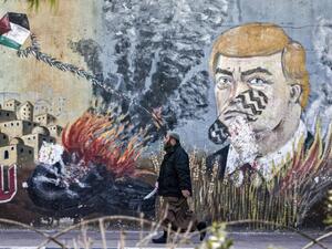 A Palestinian walks past a mural depicting US President Donald Trump with a footprint on his face, along a street in Gaza City (AFP)