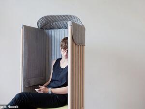 Upholstered in a soft, grey covering fabric, the chair provides a 'cosy, intimate, comfy and silent' space to isolate its occupants from the surrounding environment Upholstered in a soft, grey covering fabric, the chair provides a 'cosy, intimate, comfy and silent' space to isolate its occupants from the surrounding environment.