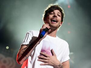 Singer Louis Tomlinson was in the baggage claim at Los Angeles International Airport with a girlfriend when he entered a tussle with a photographer (AFP Photo/KEVIN WINTER)