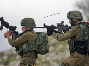 Israeli soldiers hold up their rifles towards Palestinian protesters in the village of Kfar Qaddum, near Nablus in the occupied West Bank (AFP)
