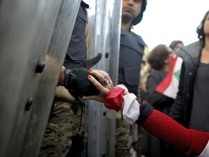 A Lebanese anti-government protester holds the hand of a Lebanese army soldier as she blocks a road leading to the parliament in the capital Beirut's downtown district on January 27, 2020. PATRICK BAZ / AFP