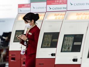In this file photo taken on March 15, 2017, a mask-clad Cathay Pacific employee walks past a row of self check-in counters at the international airport in Hong Kong. AFP