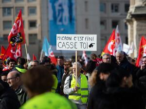 A protester wearing a yellow vest holds a sign reading "Macron, it's over, go away" as he takes part in a demonstration against the French government's plan to overhaul the country's retirement system in Marseille, southeastern France, on February 6, 2020. CLEMENT MAHOUDEAU / AFP