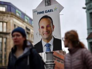 Pedestrians walk past a defaced campaign poster featuring Ireland's Prime Minister and leader of the Fine Gael party, Leo Varadkar as they walk along a street in Dublin on February 7, 2020, on the eve of the country's General Election. Ireland on Friday entered the final day of campaigning before this weekend's election, as polls predicted a historic three-way fight for control of the next government. Prime Minister Leo Varadkar, of the Fine Gael party, was canvassing in the western town of Ennis while Fian