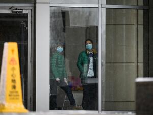 Two women wearing face mask look through a window in building in Beijing on February 14, 2020. The death toll from the COVID-19 coronavirus epidemic neared 1,400 on February 14, as the United States complained of a "lack of transparency" from Beijing over its handling of a crisis that has fuelled global panic. STR / AFP