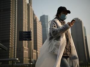 People wearing protective face masks walk on an overpass in Shanghai on February 24, 2020. China is expected to decide February 24 whether to postpone its annual parliament session for the first time since the Cultural Revolution as the country battles the COVID-19 coronavirus outbreak. Noel Celis / AFP