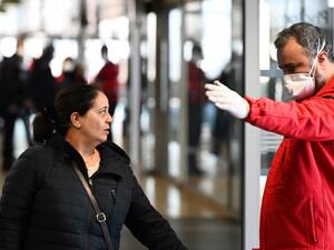A member of the Fire safety and personal assistance (Service de securite incendie et d'assistance à personnes - SSIAP) gives indications to people at the train and bus station Lyon Perrache after marking a security zone, following the blockage of a bus coming from Milan due to suspected COVID-19 the novel coronavirus on board, in Lyon, on February 24, 2020. JEAN-PHILIPPE KSIAZEK / AFP